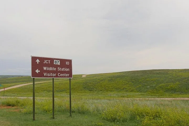 Panneau routier marron du Wildlife Station Visitor Center sur une colline herbeuse